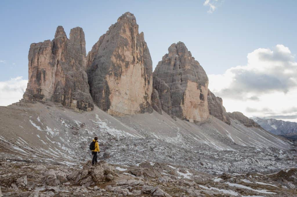Gaia standing in front of the three peaks of Tre Cime di Lavaredo wearing a yellow jacket