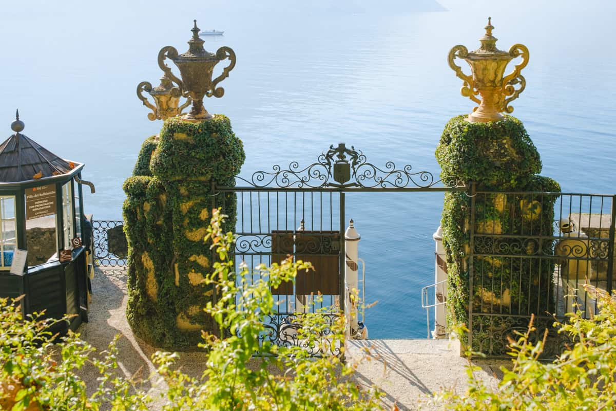 Villa Balbianello's dock where people come in when arriving from the lake. There's a big elaborated gate covered by plants and the lake on the background.