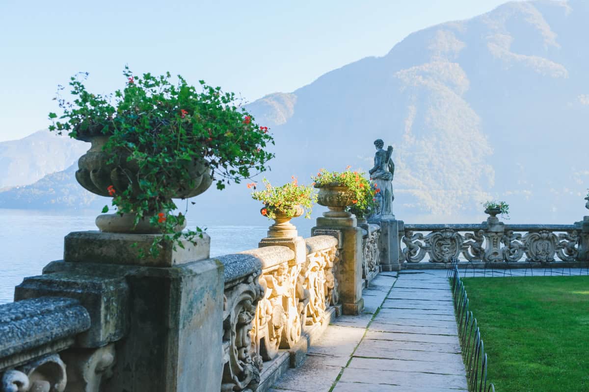 A beautiful decorated banister on a terrace at Villa Balbianello, with statues and plants.