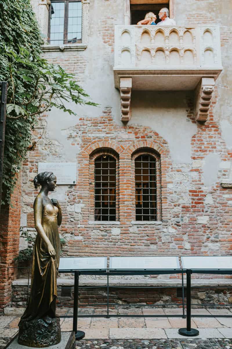 Juliet's balcony in Verona, a popular attraction linked to Shakespeare's Romeo and Juliet, with ivy-covered walls and a small stone courtyard below.