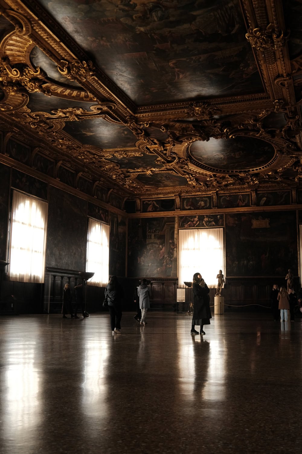 ​A woman looking up at the intricate golden ceilings inside Doge's Palace in Venice.